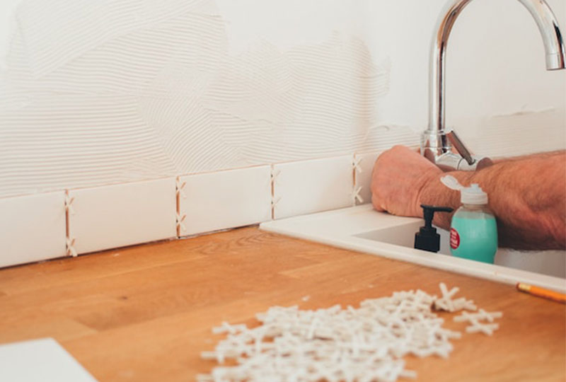 Tiler pressing horizontal white metro tiles into tile adhesive